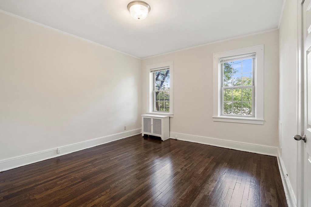 a living room with white walls and wooden floors and a window