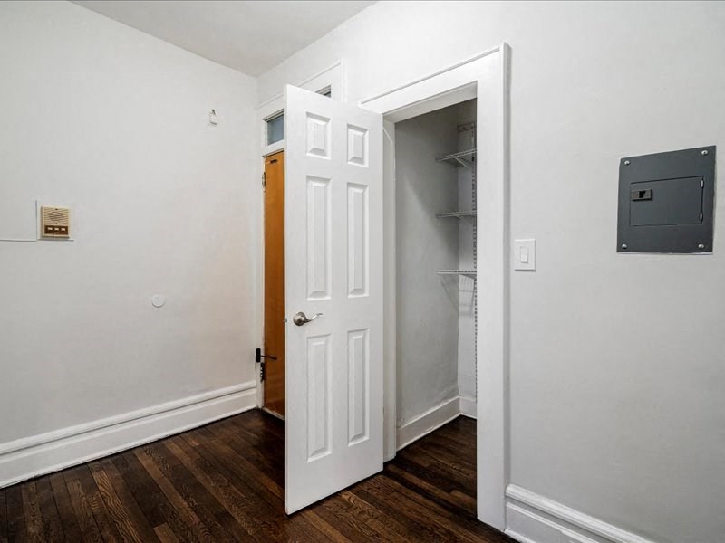 A white door is open to a hallway with wood floors.