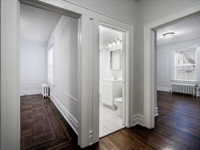 A white bathroom with wood floors and a window.