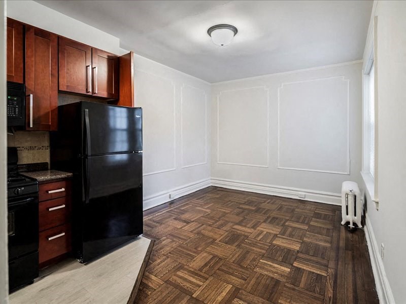 A kitchen with black appliances and wooden flooring.