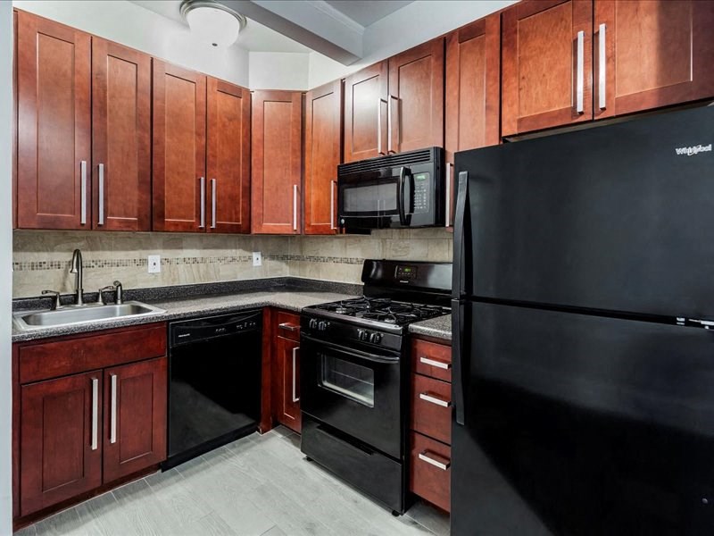 A kitchen with black appliances and wooden cabinets.