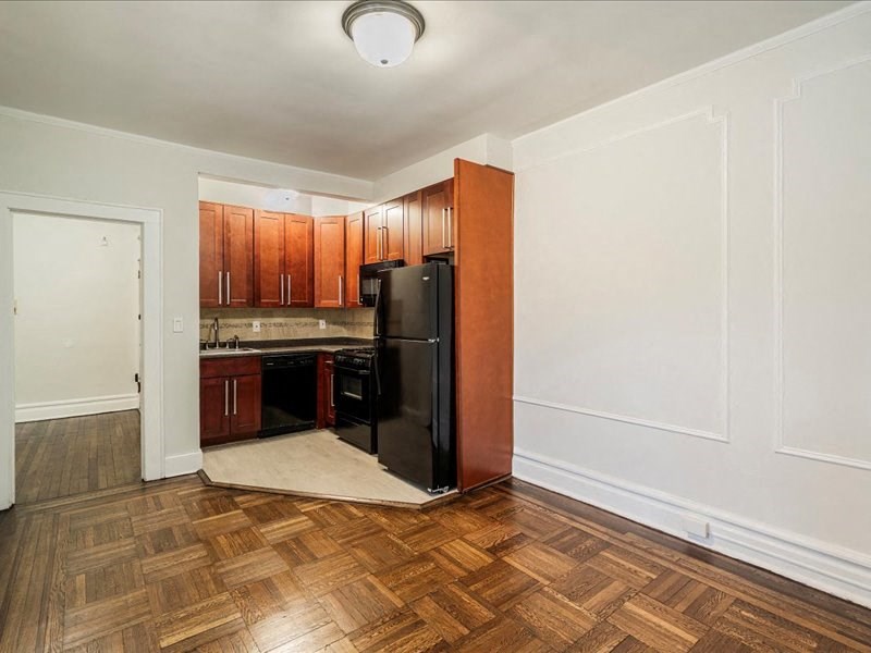 A kitchen with wooden cabinets and a black refrigerator.