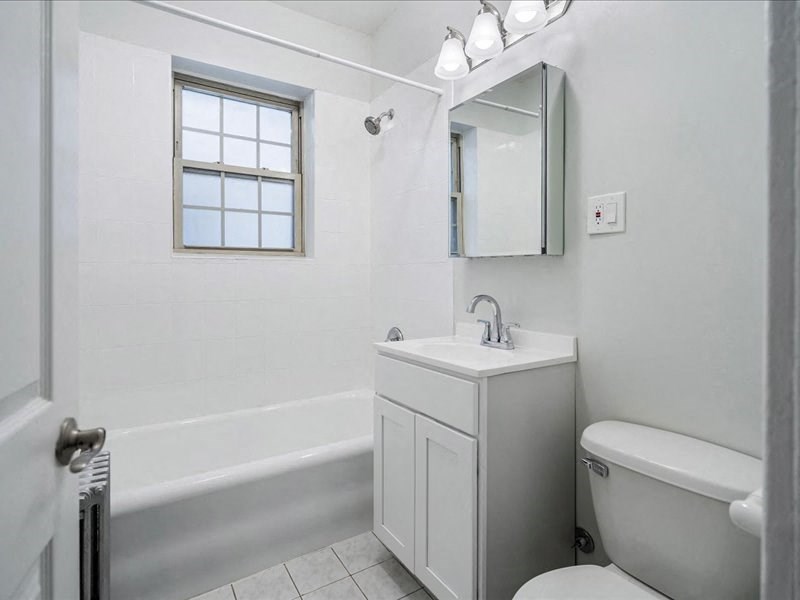 A white bathroom with a sink, mirror, and bathtub.