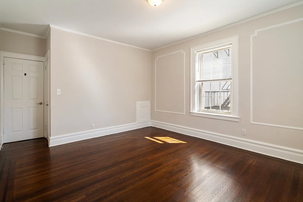 an empty living room with wood floors and a window