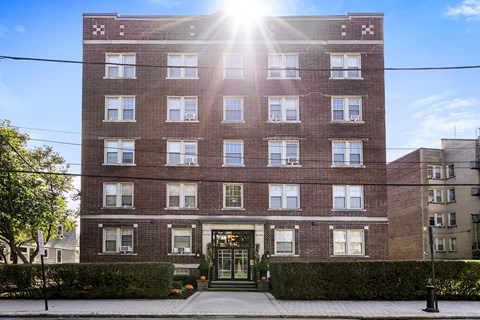 a brick apartment building with the sun shining in front of it