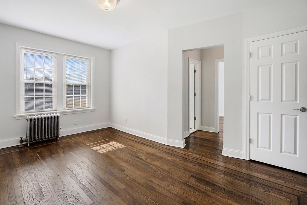 an empty living room with wood floors and white walls