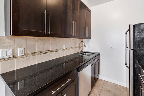 a kitchen with dark cabinets and a sink and a refrigerator
