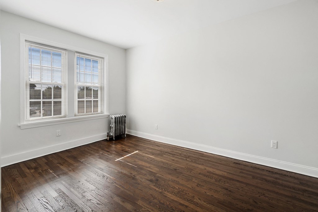an empty living room with wood flooring and a window