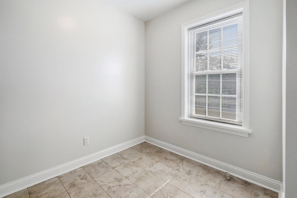 an empty room with a window and a tiled floor