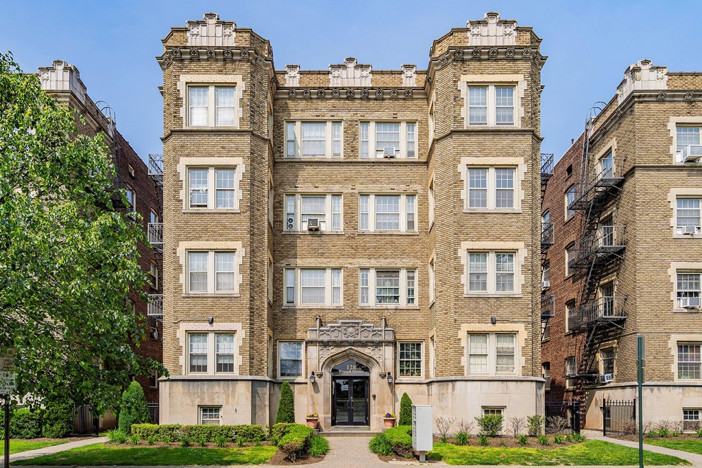 a large brick apartment building with a sidewalk in front of it