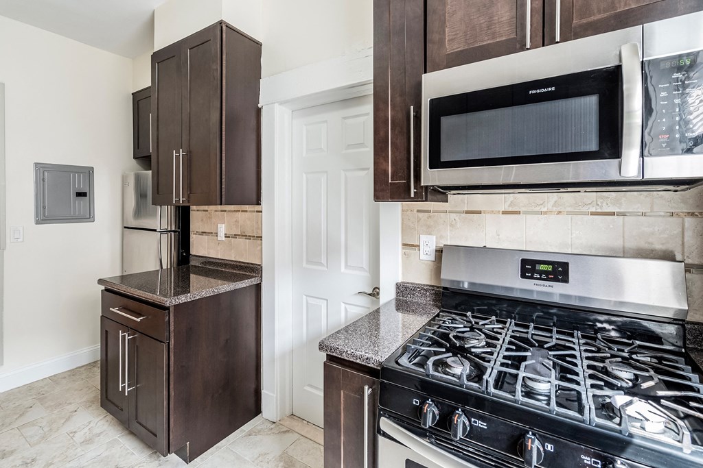 a kitchen with dark wood cabinets and a stove and microwave