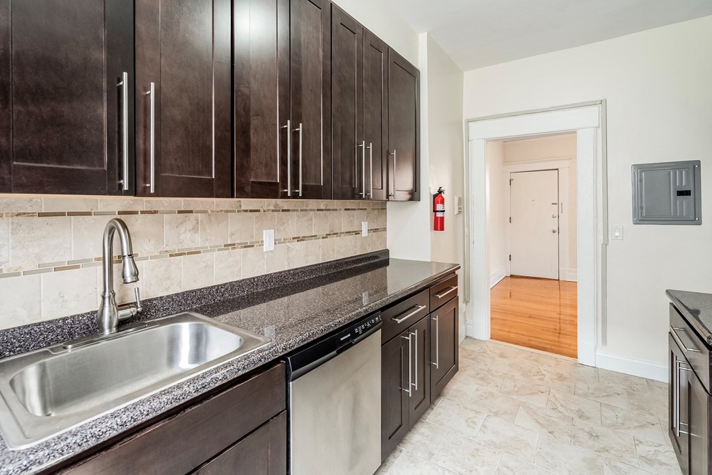 a kitchen with dark wood cabinets and a stainless steel sink