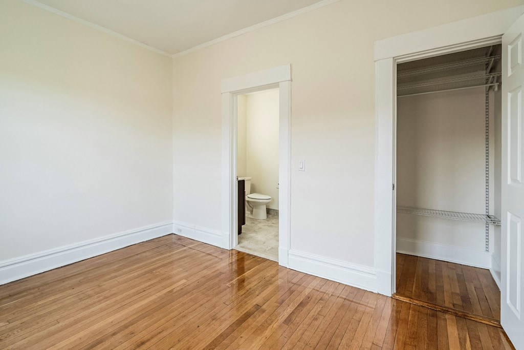 an empty room with a wooden floor and a door to a bathroom