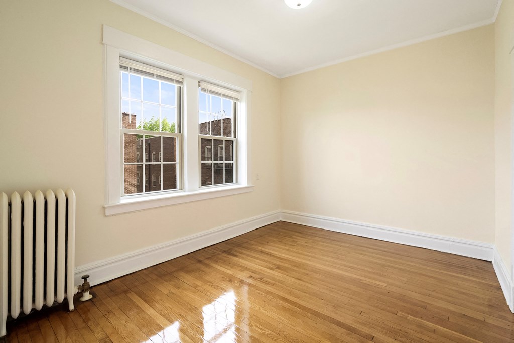 an empty room with a radiator and two windows