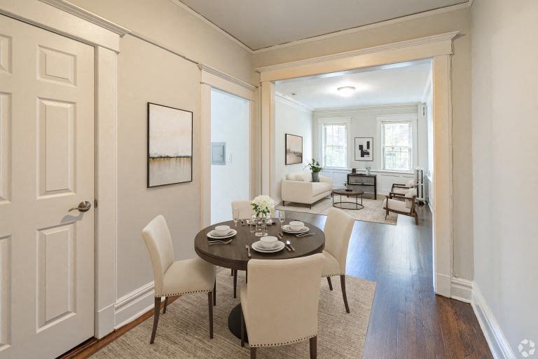 A dining room with a table set for two and chairs around it.