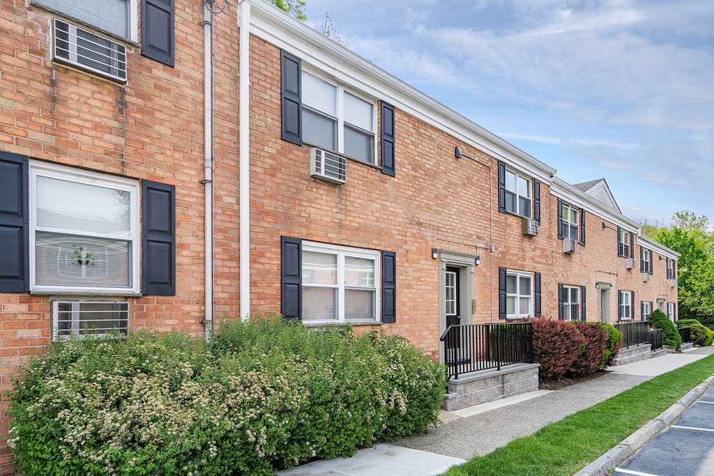a brick building with black windows and a sidewalk