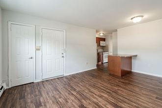 an empty living room and kitchen with a hard wood floor