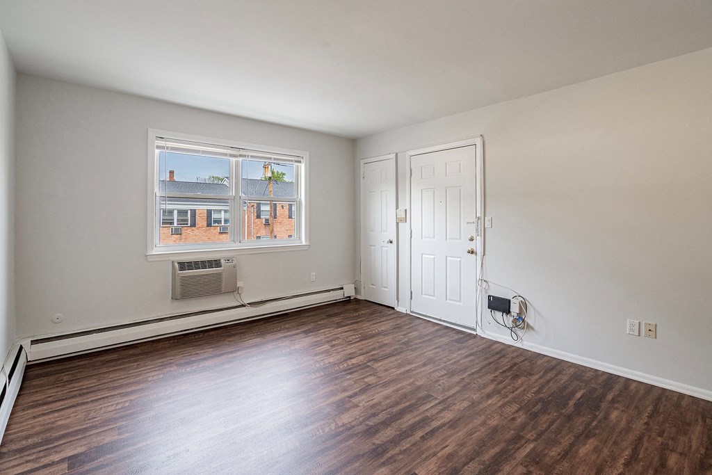 an empty living room with wood flooring and a window
