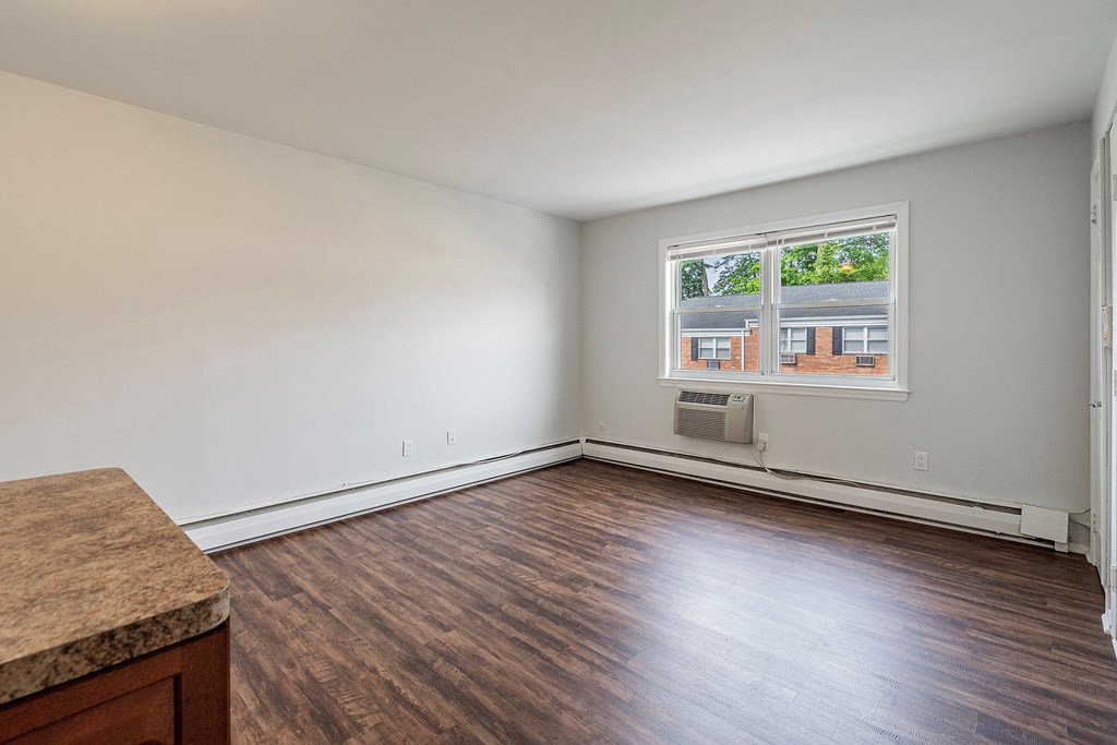 an empty living room with wood floors and a window