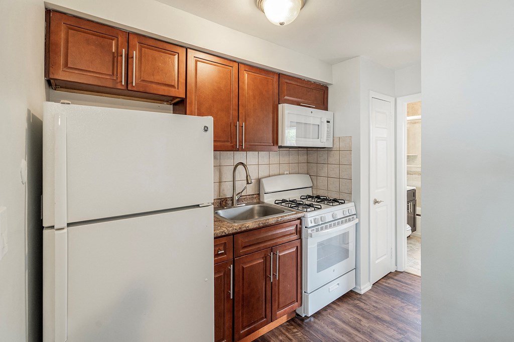 an empty kitchen with white appliances and wooden cabinets