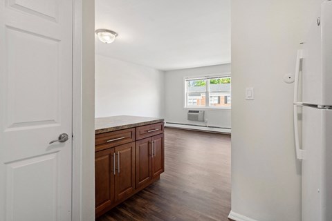 an empty kitchen and living room with a refrigerator and a window