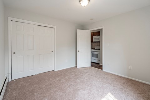 an empty living room with a door to a kitchen
