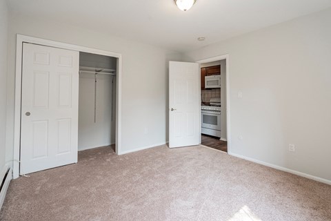 an empty bedroom with a closet and an open door to the kitchen