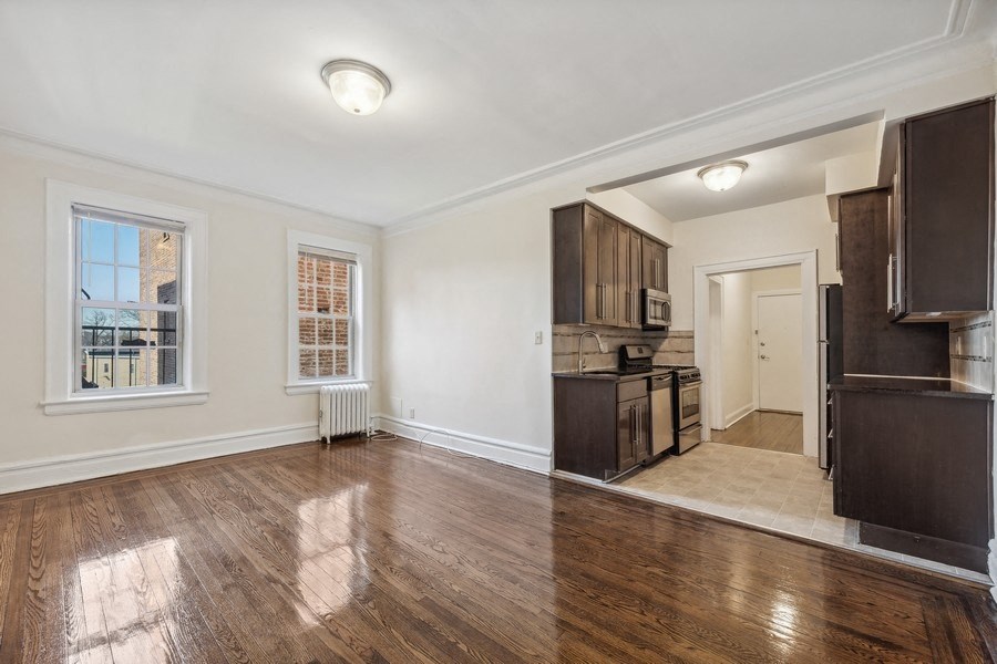 the living room and kitchen of an empty house with wooden floors and a large window