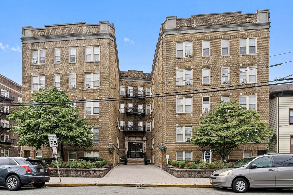 a large brick apartment building with cars parked in front