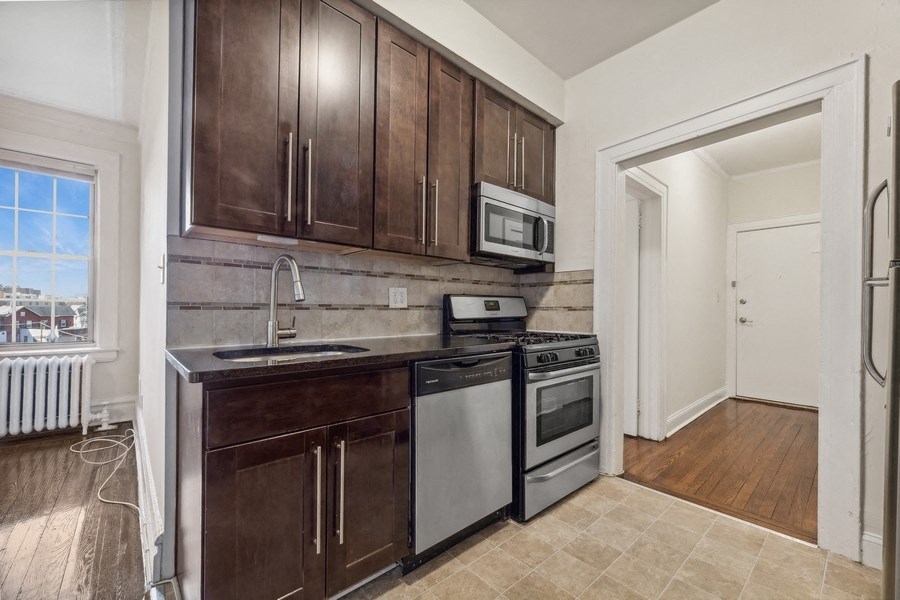 a kitchen with wooden cabinets and appliances and a window