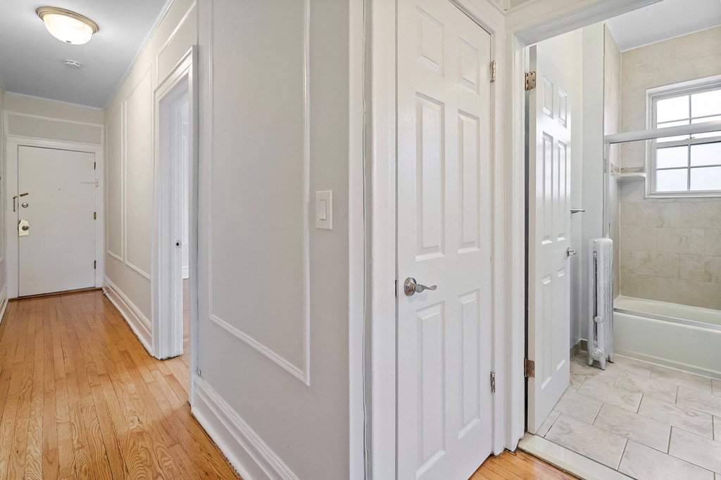 the hallway of a home with white walls and wood floors
