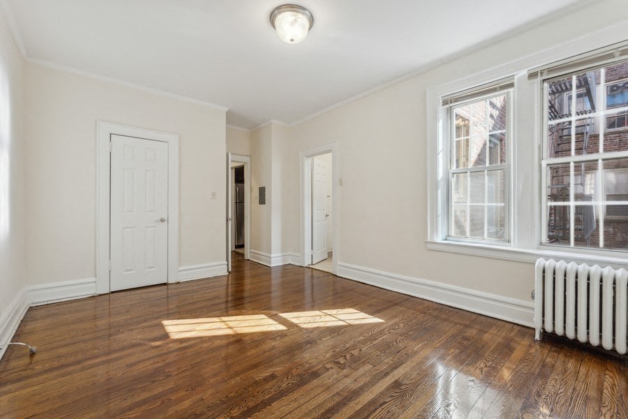 an empty living room with a radiator and a window