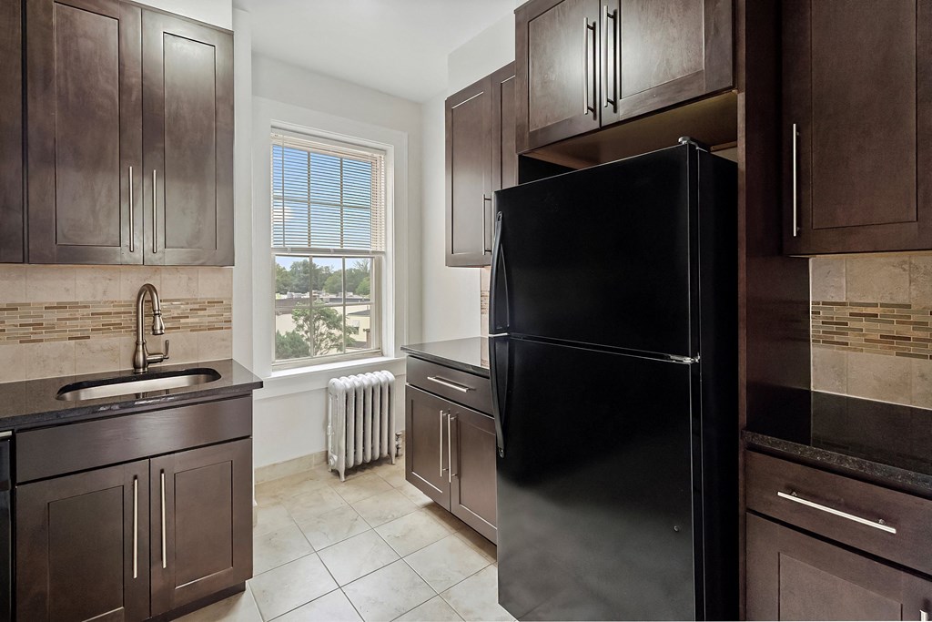 a kitchen with dark wood cabinets and a black refrigerator