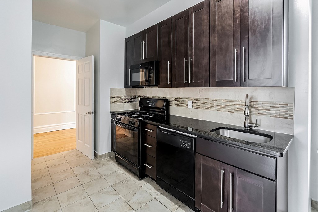 an empty kitchen with black appliances and wooden cabinets
