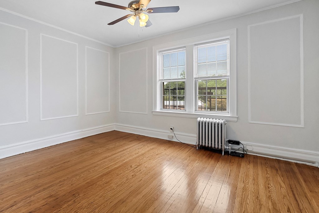 an empty room with white walls and wood floors and a ceiling fan