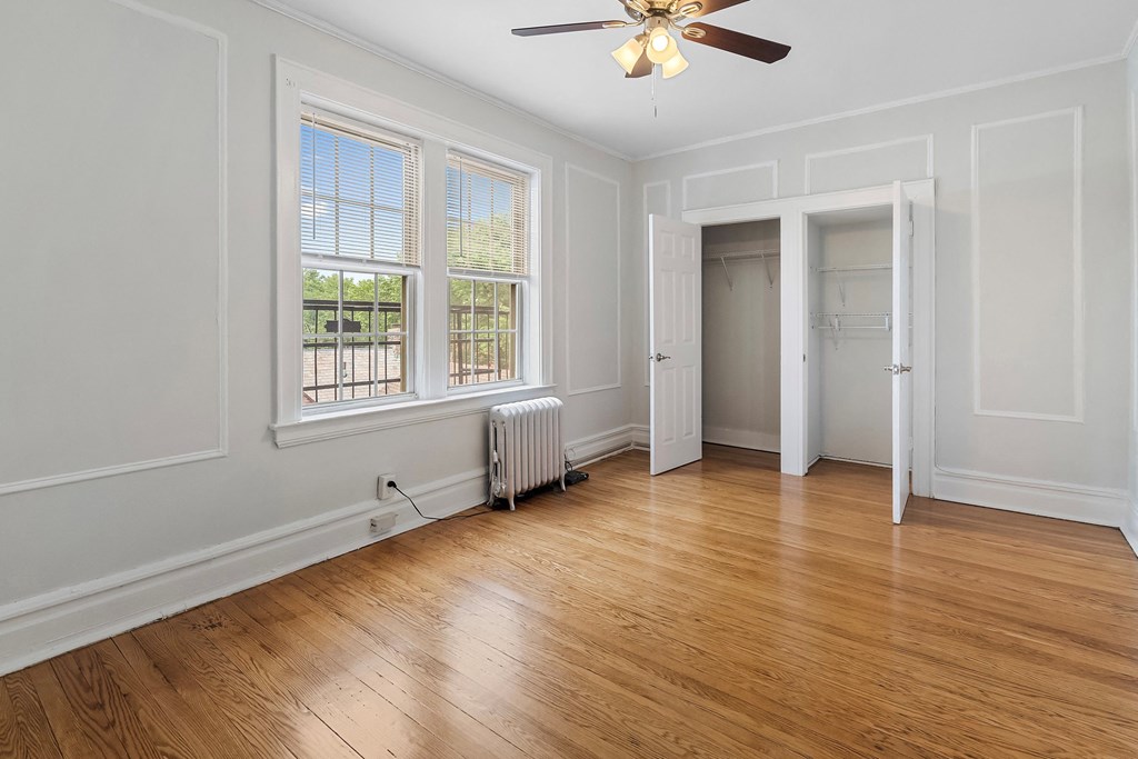 an empty living room with wood floors and a ceiling fan