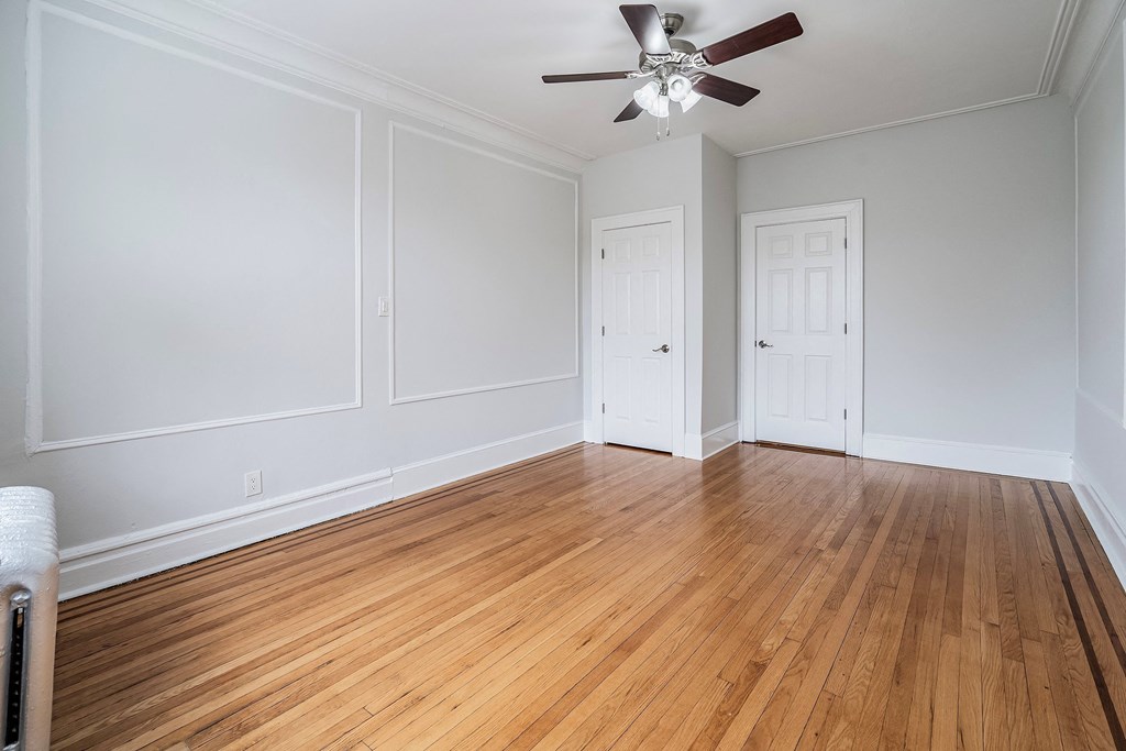 an empty living room with wood floors and a ceiling fan