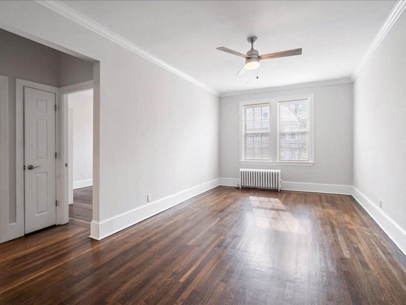 an empty living room with wood floors and a ceiling fan