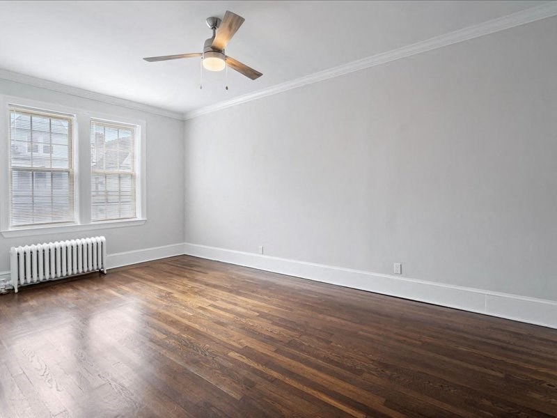 an empty living room with wood floors and a ceiling fan
