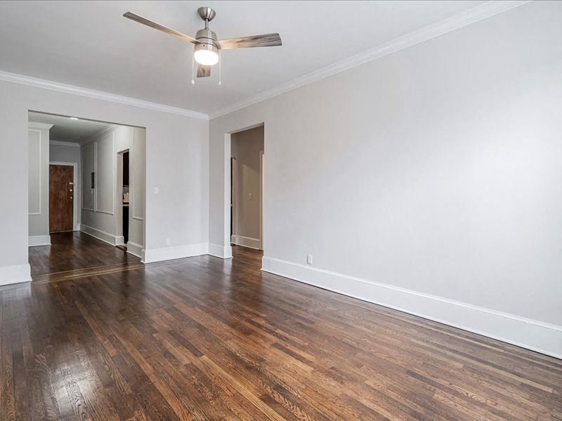 an empty living room with wood floors and a ceiling fan