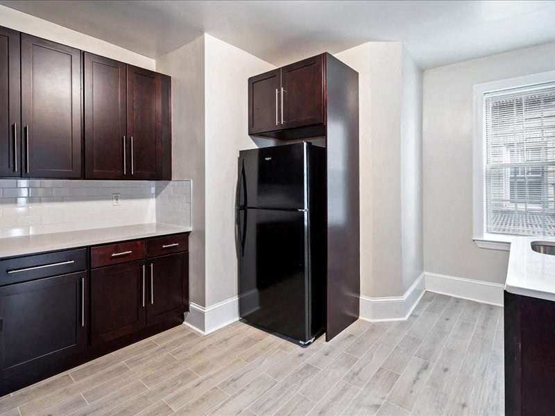 a kitchen with a black refrigerator and cabinets