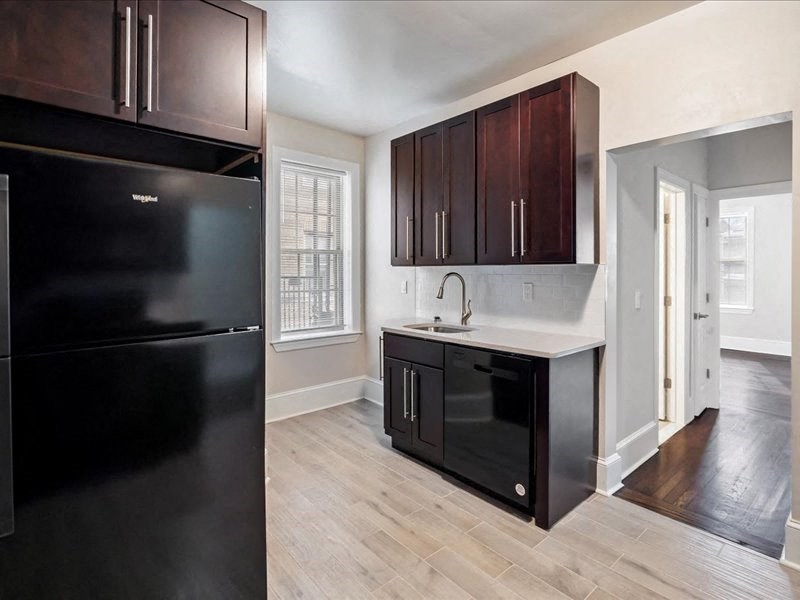 a kitchen with a black refrigerator and wooden floors