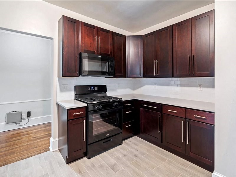 a kitchen with dark wood cabinets and a stove and a microwave
