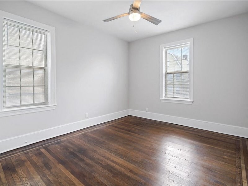 an empty room with a ceiling fan and two windows
