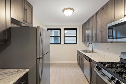 an empty kitchen with stainless steel appliances and marble counter tops