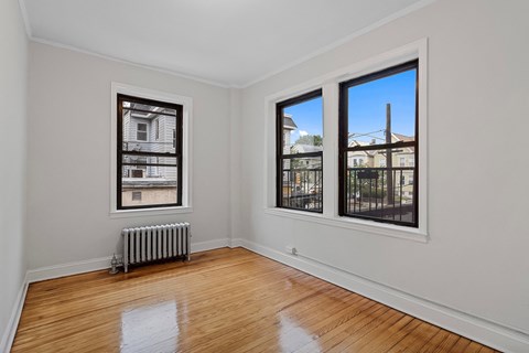 a living room with windows and a radiator and a wood floor