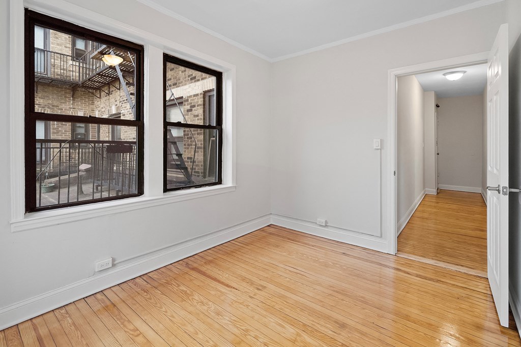 an empty living room with two windows and a wooden floor