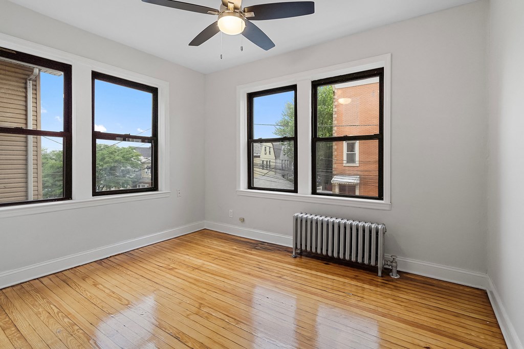 an empty room with wood floors and a ceiling fan