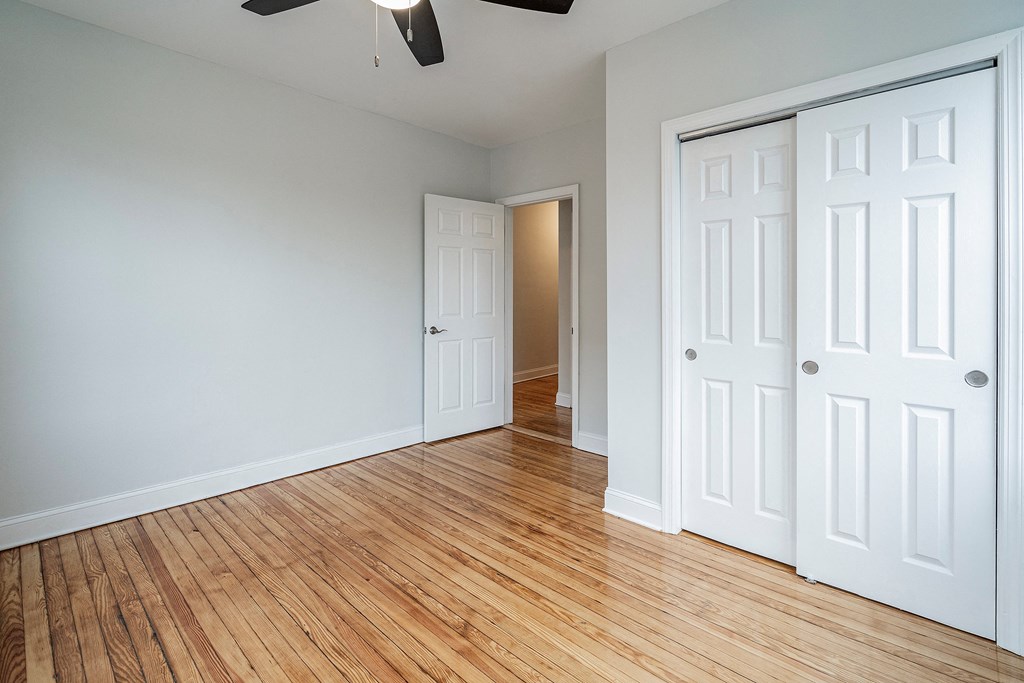 an empty room with wood floors and white closets