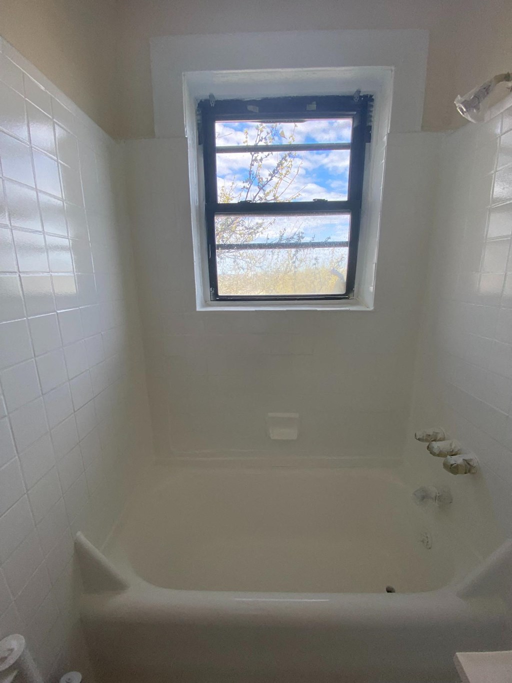 a small bathroom with a window above a bath tub
